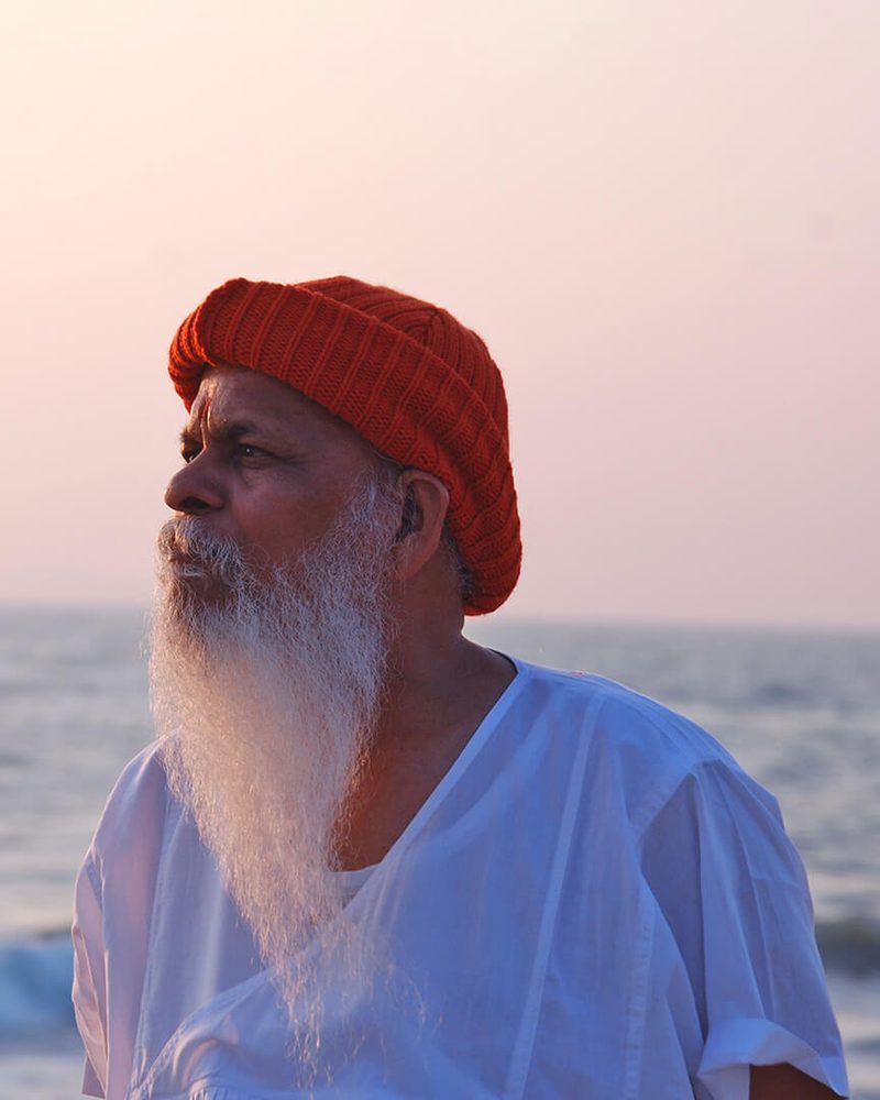 H.H. Shree Shivkrupanand Swamiji at the seashore at dusk, looking out over the water